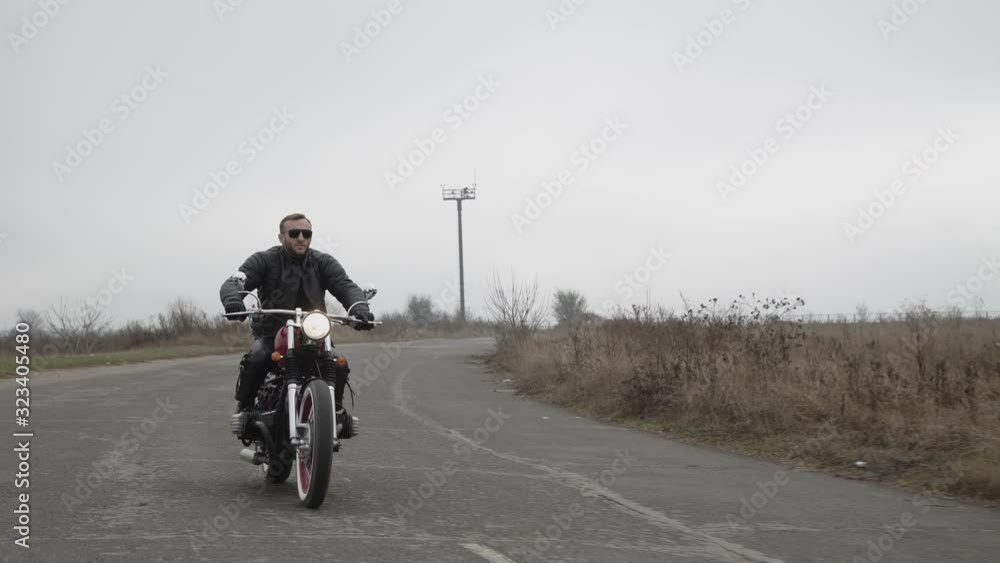 View of brutal man in sunglasses riding on motorcycle on the highway View of brutal man in sunglasses riding on motorcycle on the highway