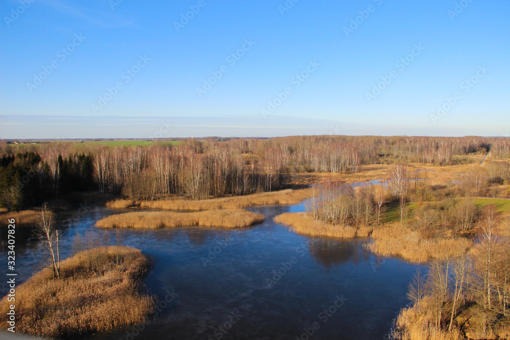The National park with karst lakes and flooded old grass meadow in Kirkilai, Lithuania. Walk at the wetland reserve on a sunny winter day. 
