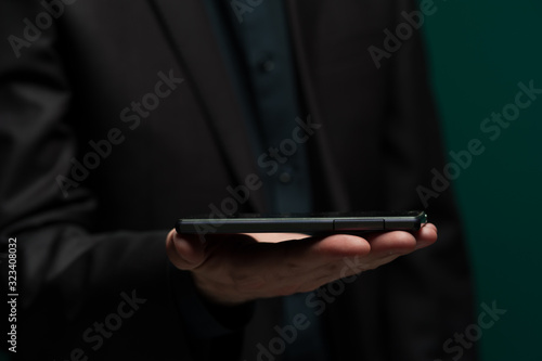 Man in dark shirt and jacket holds smartphone