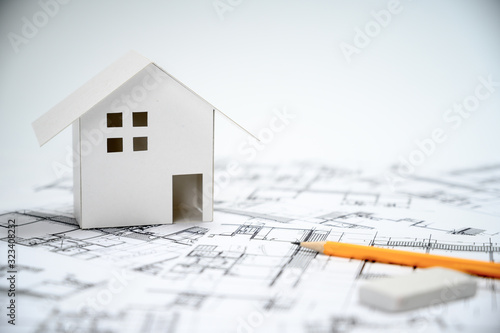 Construction industry concept with pencils and house models on architectural drawings.