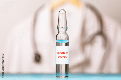 Ampoule with a vaccine from the new coronavirus COVID-19 on the background of a medical coat