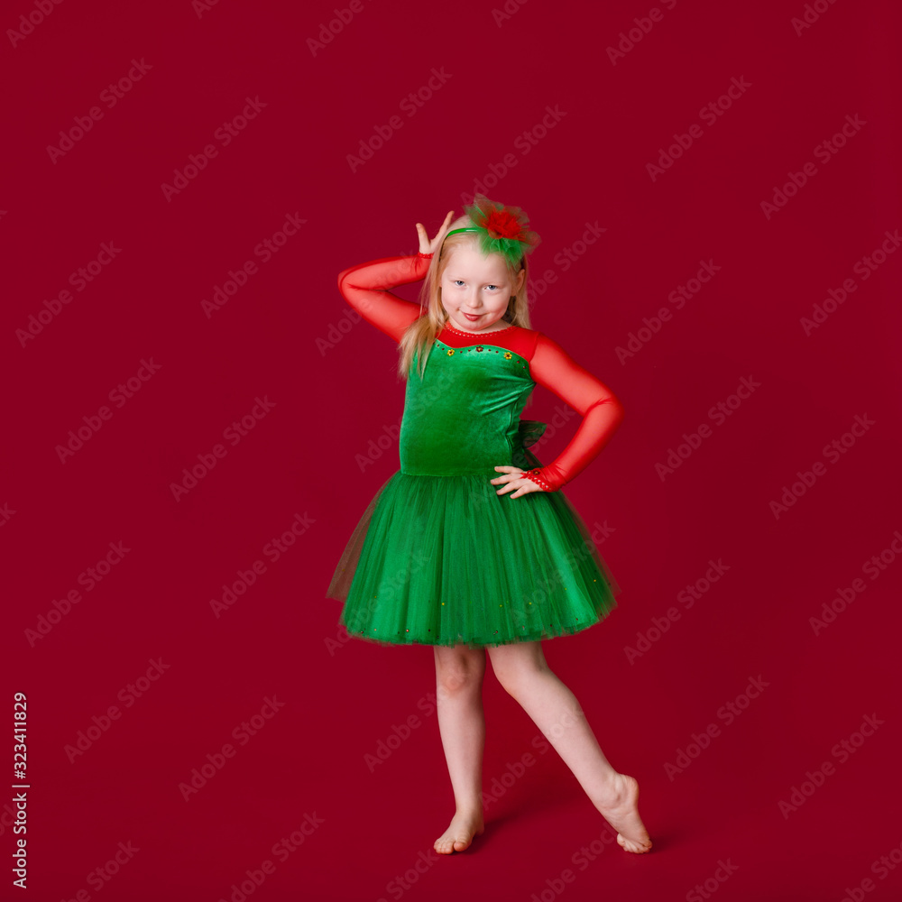 Beautiful little plump girl princess dancing in luxury green dress isolated on red background. Carnival party with costumes Beautiful little plump girl princess dancing in luxury green dress isolated on red background. Carnival party with costumes