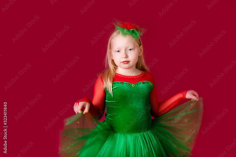Beautiful little plump girl princess dancing in luxury green dress isolated on red background. Carnival party with costumes Beautiful little plump girl princess dancing in luxury green dress isolated on red background. Carnival party with costumes