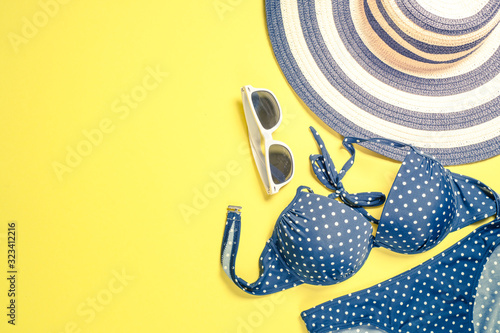 Summer travel vacation concept. Striped hat, swimsuit and sunglasses on yellow. photo