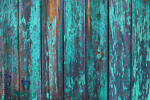 Old worn wooden planks with worn, cracked paint of a turquoise-green color with rust. Beautiful wooden aged background.