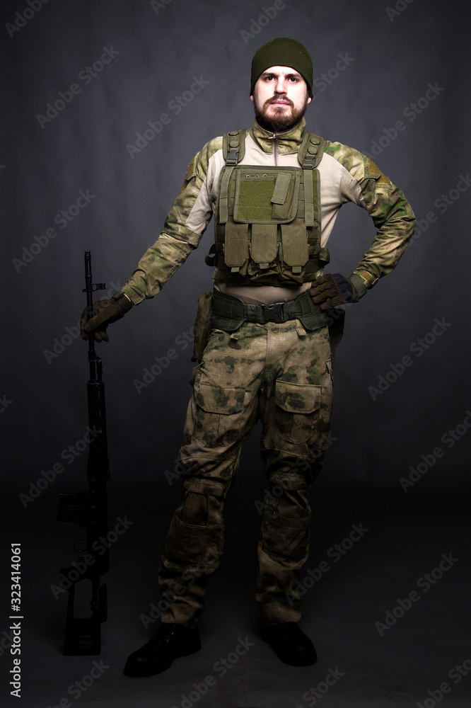 Fototapeta premium A soldier in camouflage clothing poses in a Studio