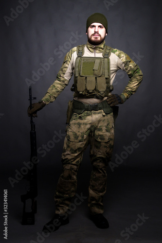 A soldier in camouflage clothing poses in a Studio