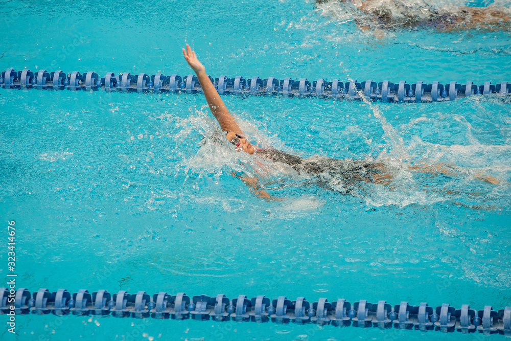 Swimming athlete girl with backstroke during competition