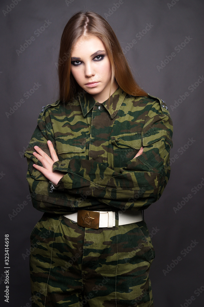 A girl soldier in camouflage clothing poses in a Studio A girl soldier in camouflage clothing poses in a Studio