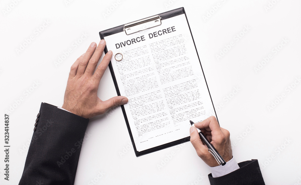 Hands of husband signing decree of divorce, canceling marriage Hands of husband signing decree of divorce, canceling marriage