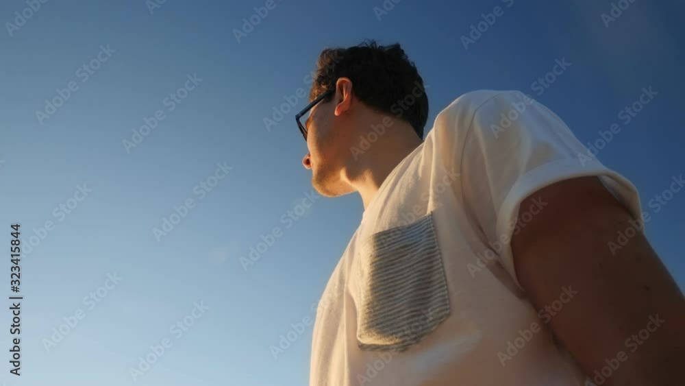 man in sunglasses and white t-shirt at sunset low angle shot man in sunglasses and white t-shirt at sunset low angle shot