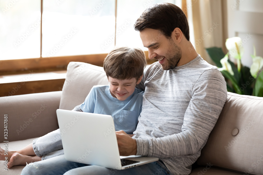 Overjoyed school boy enjoying funny movie on computer with dad. Overjoyed school boy enjoying funny movie on computer with dad.