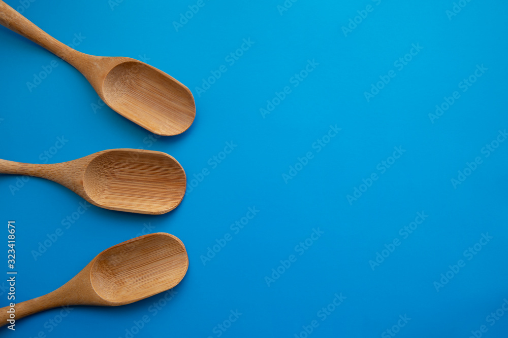 Eco bamboo wooden spoons on the blue table. Empty space for design Eco bamboo wooden spoons on the blue table. Empty space for design