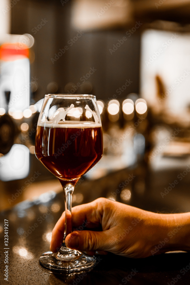 man holds a glass of beer in his hand at the bar or pub