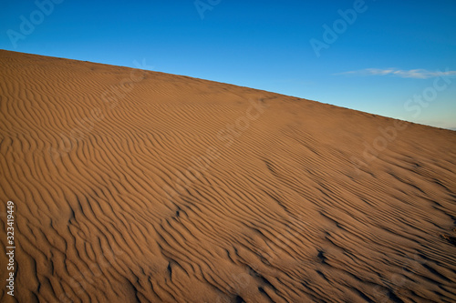 Abstract of textured sand dune against blue sky. Corralejo, Fuerteventura, Spain.