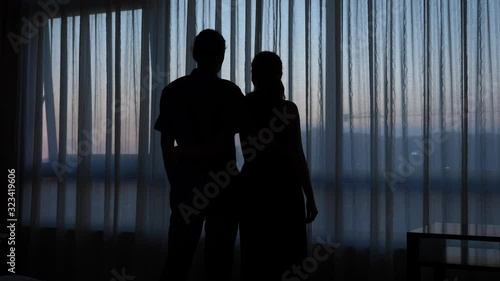 Romantic couple silhouette against window at sunset
