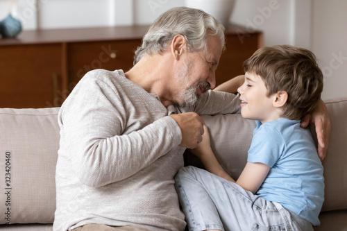 Pleasant middle aged man having sincere trustful conversation with grandchild.