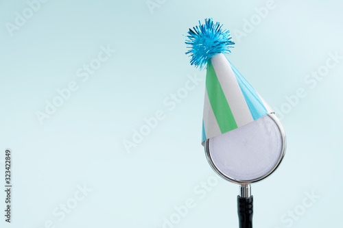 Doctor's day and World health day concept. Medical stethoscope in a festive cap on light blue background. Creative medical background, postcard. Copy space, close up photo