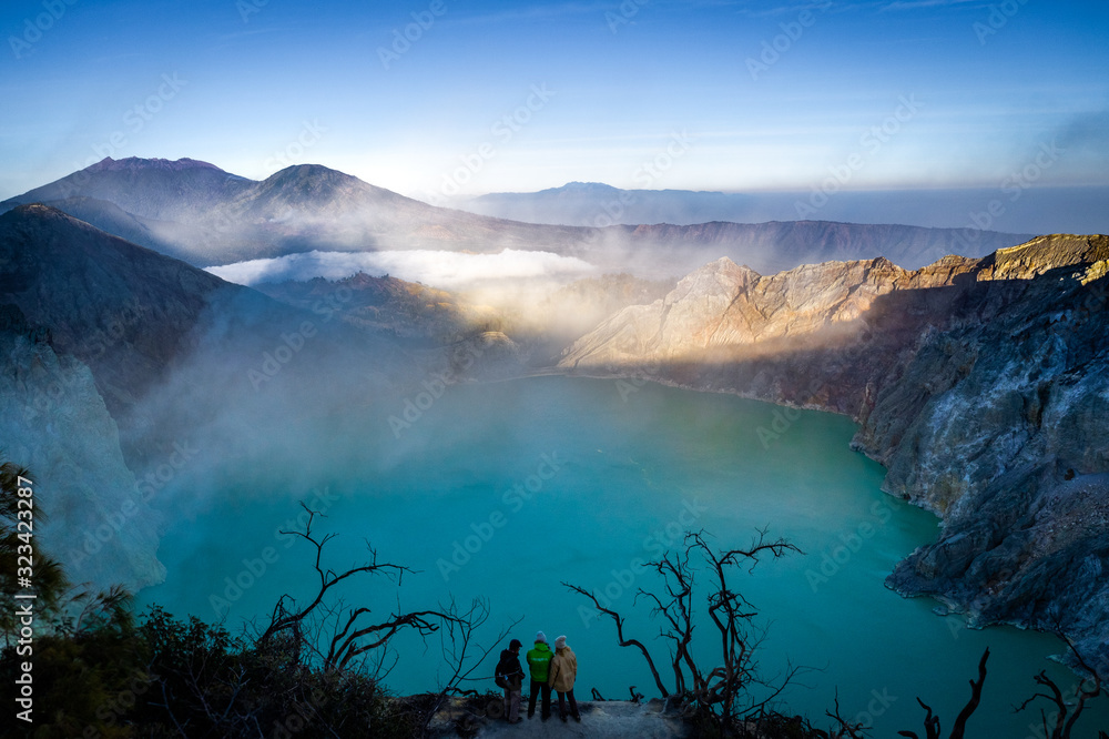 people standing on the edge of the lake in vulcano ijen