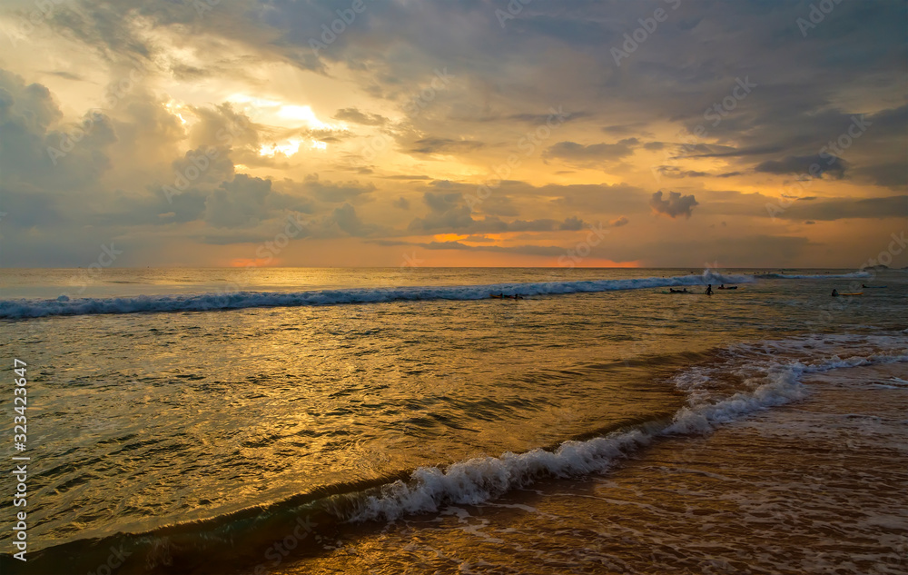 Fototapeta premium Reflection of vivid sunset sky over sea and beach.Colorful sunrise with Clouds over ocean. Pink and yellow sunset over the ocean with clouds, Sri Lanka, Asia, Ceylon