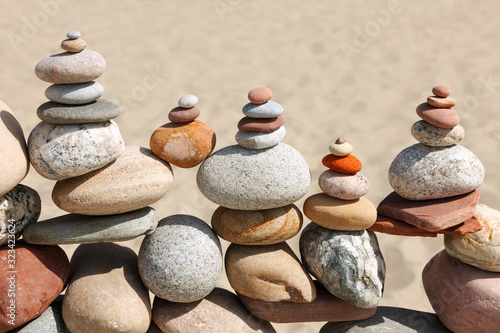 Lots of balanced  colorful pebbles on a beach on the background of the sand.