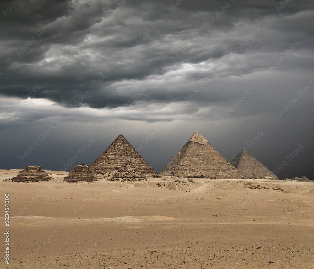 The Giza pyramid complex under dramatic grey stormy sky