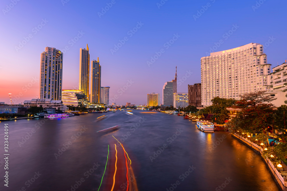 Obraz premium Skyscrapers and small traffic routes along the Chao Phraya River in Bangkok as seen from the Taksin Bridge at night. Bangkok, Thailand
