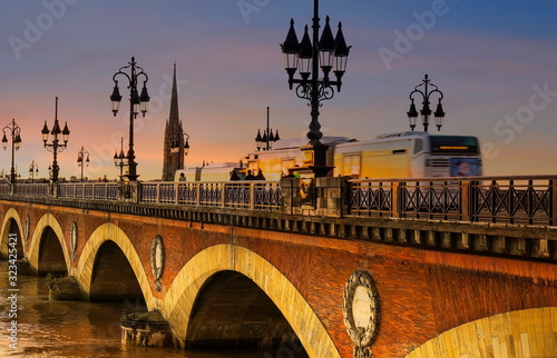 Selective focus of  Pont de Pierre bridge and motion blur of tram in Bordeaux at sunset as the night sky scene © SASITHORN