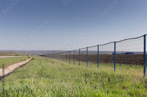 Beautifu spring landscape and a modern metal fence.