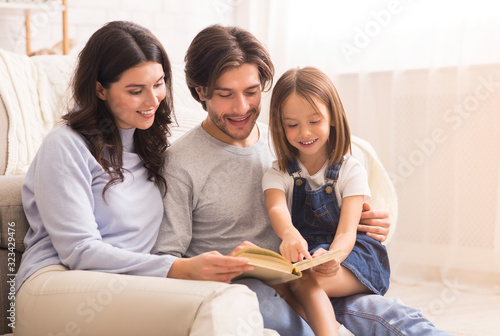 Parents teaching their little daughter how to read at home