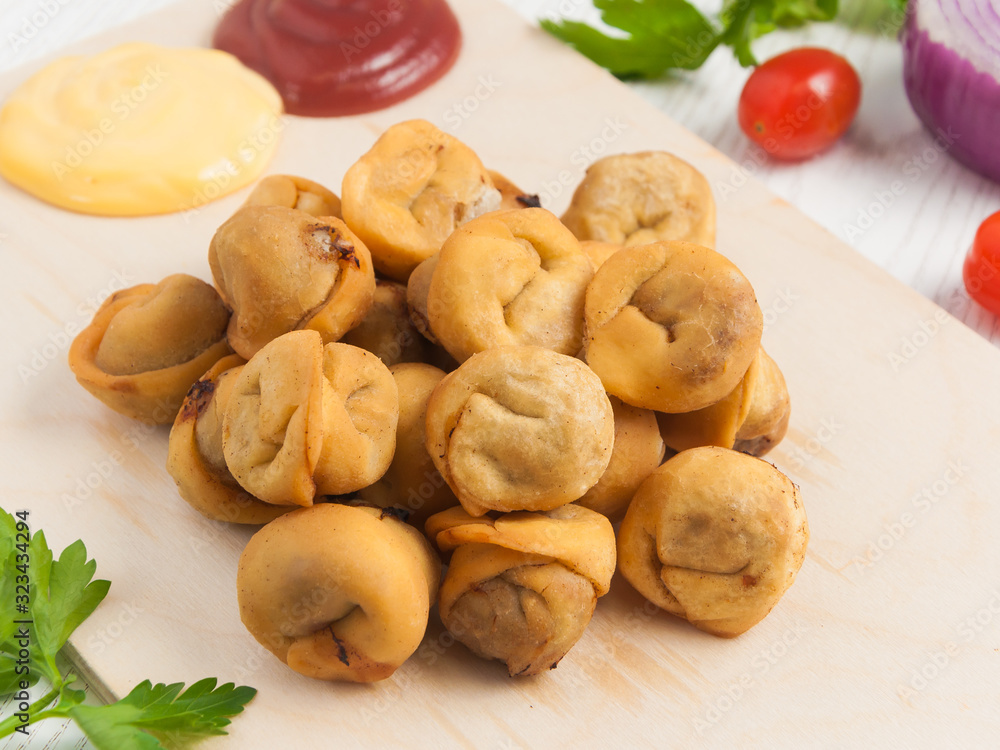 deep-fried dumplings on a wooden Board with tomato and cheese sauce deep-fried dumplings on a wooden Board with tomato and cheese sauce