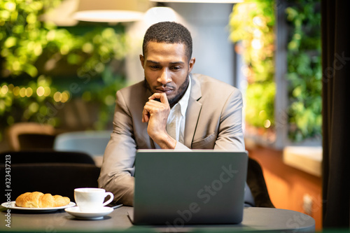 Black guy sitting in coffee shop working on pc