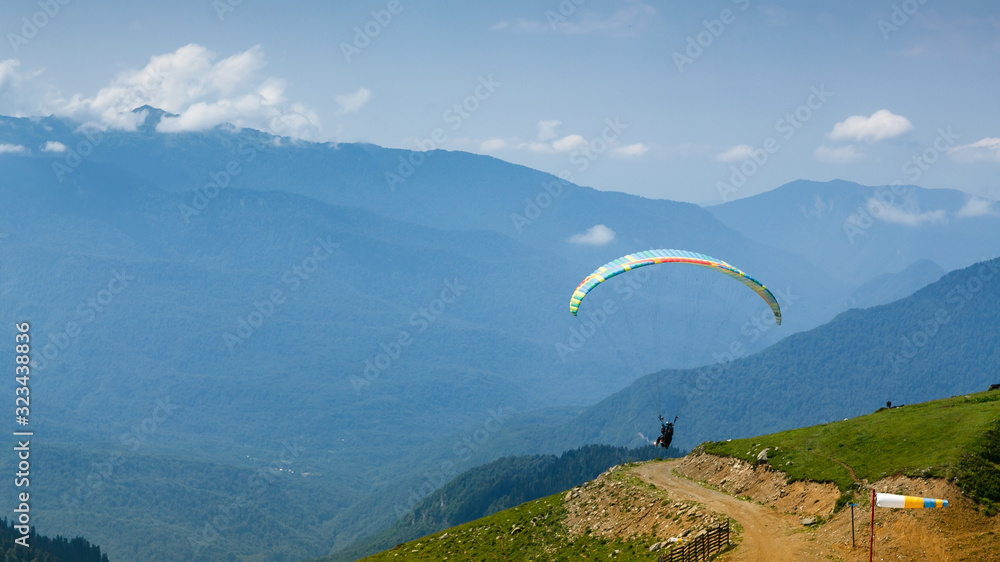 A tourist with an instructor flies a paraglider on the background of a beautiful mountain landscape. Extreme sports in the mountains. A tourist with an instructor flies a paraglider on the background of a beautiful mountain landscape. Extreme sports in the mountains.