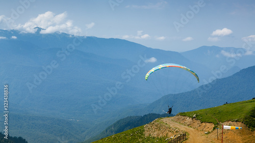 A tourist with an instructor flies a paraglider on the background of a beautiful mountain landscape. Extreme sports in the mountains.