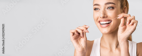 Obraz na płótnie Smiling Woman Flossing Perfect Teeth Standing Over Gray Background, Panorama