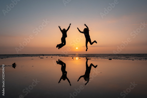silhouette of two girls jumping cheerful and happiness during sunrise
