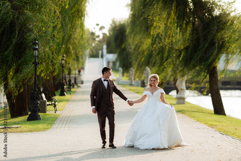 Full length body portrait of young bride and groom running on green grass of golf course, back view. Happy wedding couple walking through golf course, copy space Full length body portrait of young bride and groom running on green grass of golf course, back view. Happy wedding couple walking through golf course, copy space