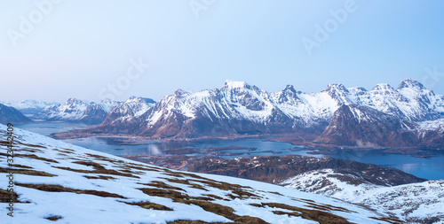 Panorama of Landscape shot from Ryten towards fredvang and ramberg in Lofoten island in Norway during blue hour. Snow cover the peaks and city lights in the background. © Jon Anders Wiken