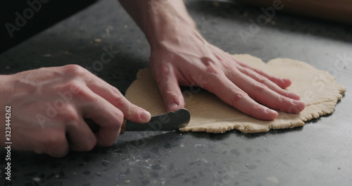 man cutting flat dough with knife