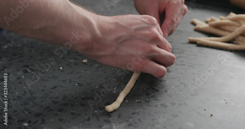 man making grissini on concretre countertop