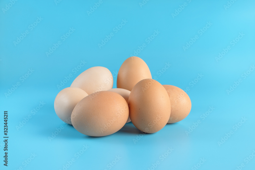 Seven fresh brown chicken eggs on a blue background. Healthy good nutrition. Natural organic farm products. Seven fresh brown chicken eggs on a blue background. Healthy good nutrition. Natural organic farm products.
