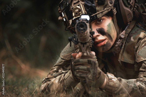close up of woman soldier holding gun laying on the ground