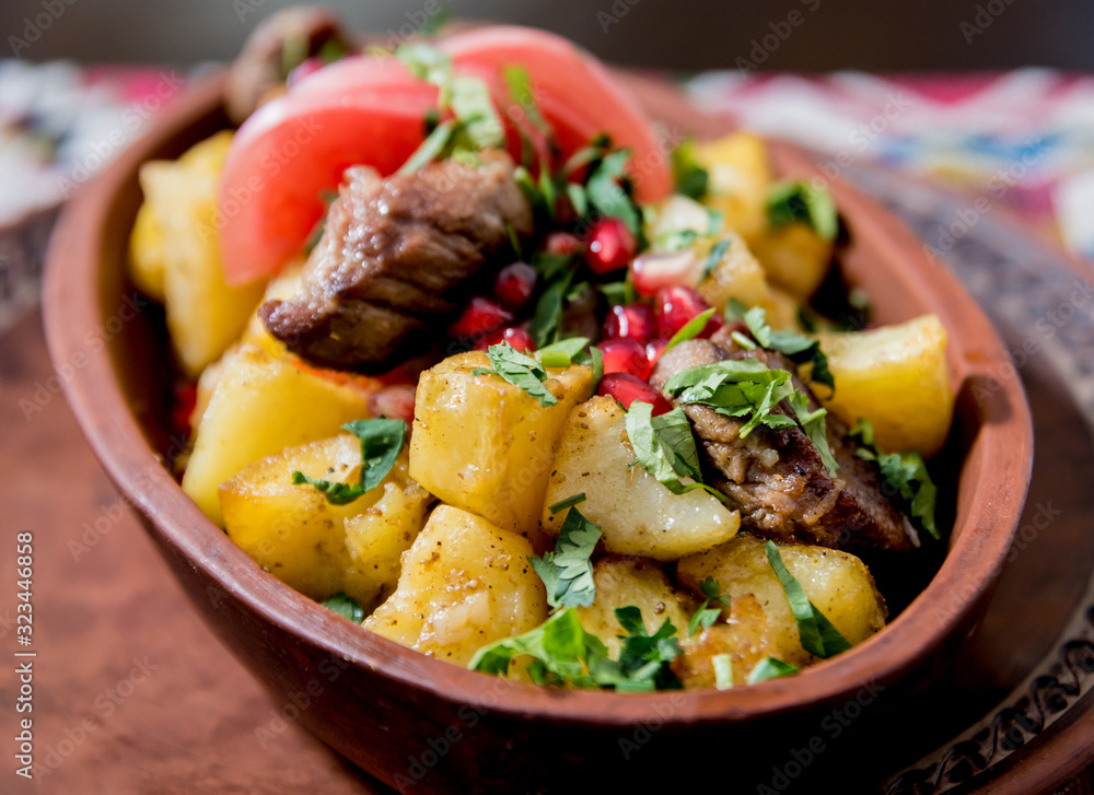 Fried potatoes with pieces of meat in a clay pot. European cuisine. Fried potatoes with pieces of meat in a clay pot. European cuisine.