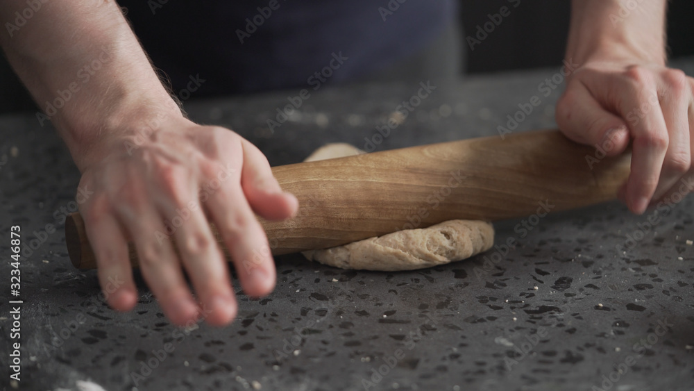 man rolling dough on concretre countertop man rolling dough on concretre countertop