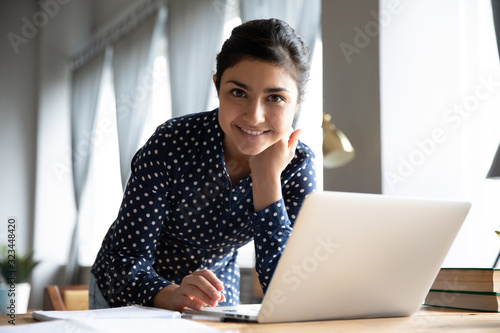 Portrait of smiling Indian girl busy working on laptop