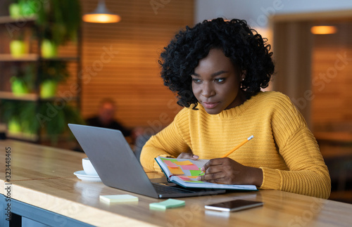 Concentrated black girl browsing job opportunities on laptop
