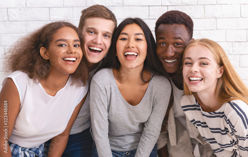 Portrait of happy multiethnic young friends over white wall background photo