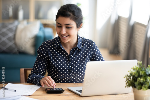 Millennial indian woman paying bills on laptop online photo