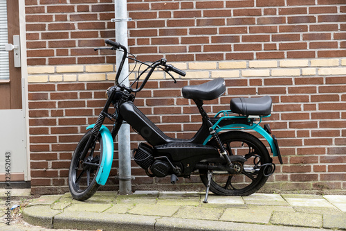 Photography Black and green moped left behind with a lock on the rear wheel and also a flat