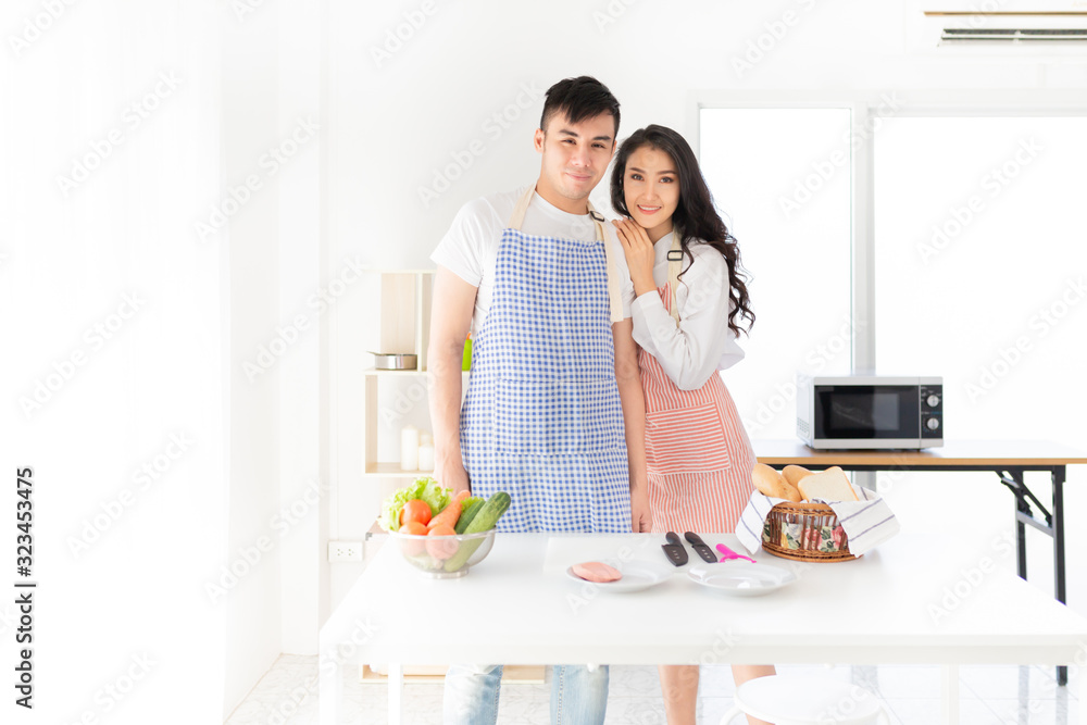 asian man and asian woman cooking organic sandwich in kitchen, they feeling happy and smile, asian female rest chin on shoulder of her husband asian man and asian woman cooking organic sandwich in kitchen, they feeling happy and smile, asian female rest chin on shoulder of her husband